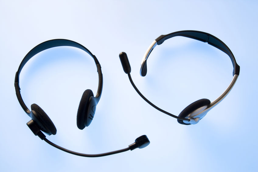 Two black headsets with microphones are placed on a light blue background.